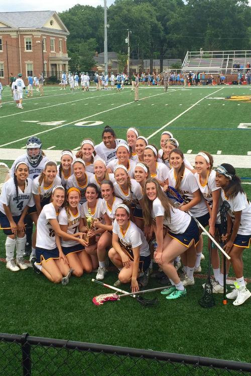 Girls Lacrosse players eagerly show off their new trophy.