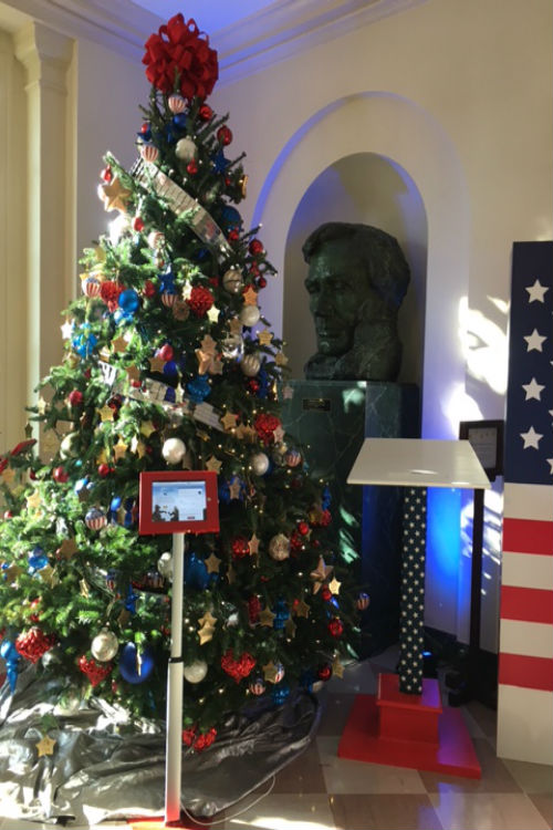 A huge bust of Lincoln sits behind one of the Christmas trees. 