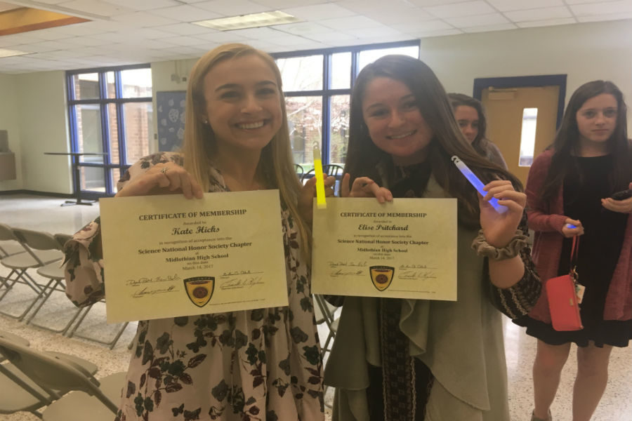 Kate Hicks and Elise Pritchard show off their SNHS certificates and glow sticks.