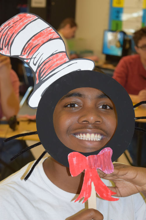 Joshua Burkes celebrates Dr. Seuss legacy by holding up a Cat in the Hat mask. 