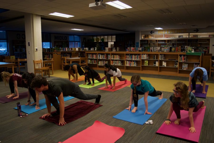 Yoga Club members move into low right lunge pose.