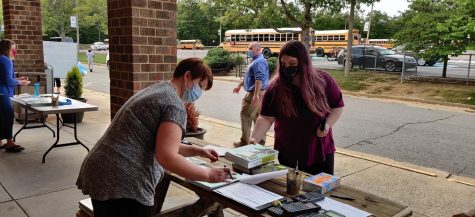 Mrs. Emilia Evans issues a textbook in Midlo Librarys textbook distribution 2020.