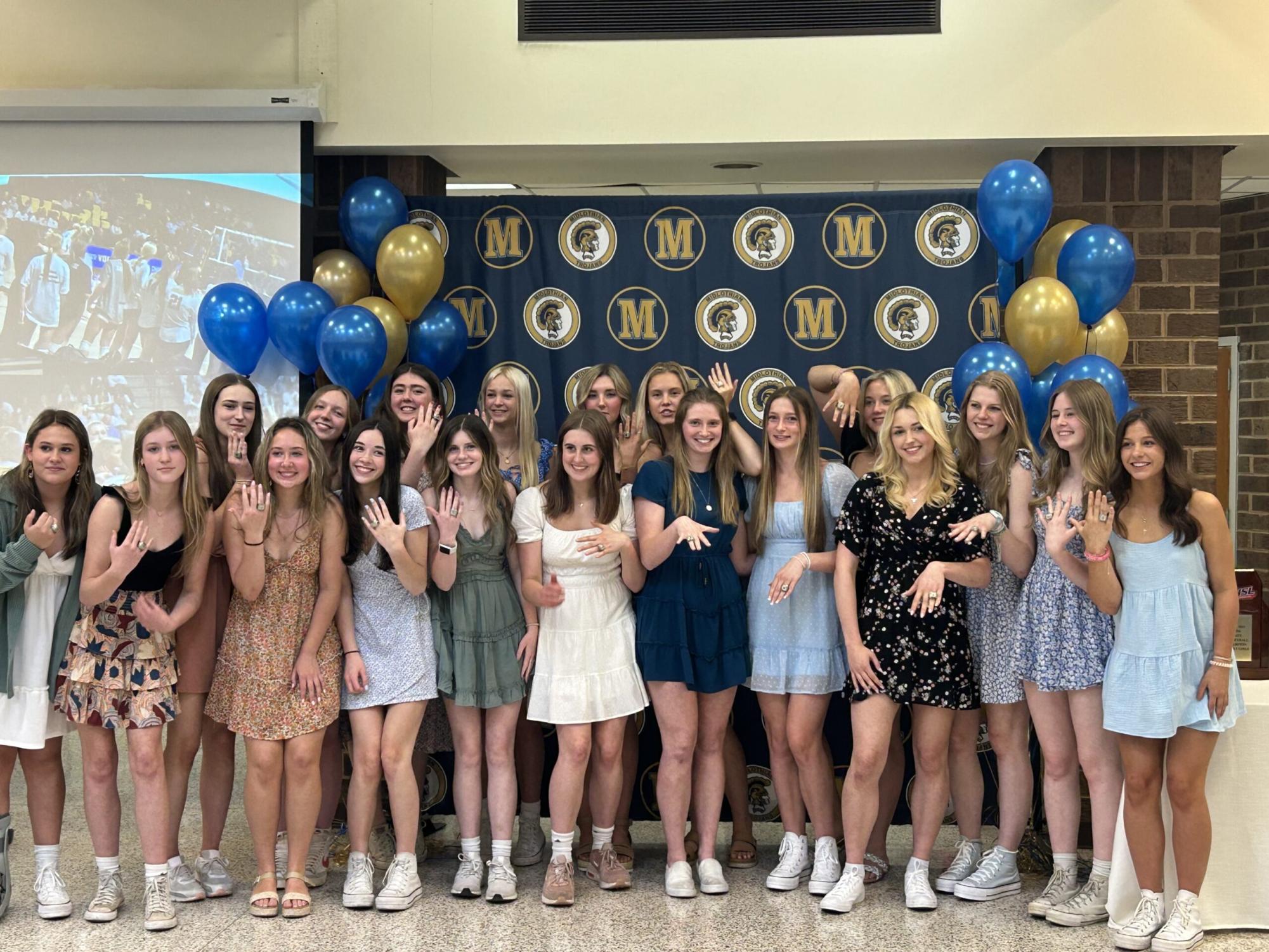 Girls Volleyball taking a team picture with their championship rings during an April ceremony.