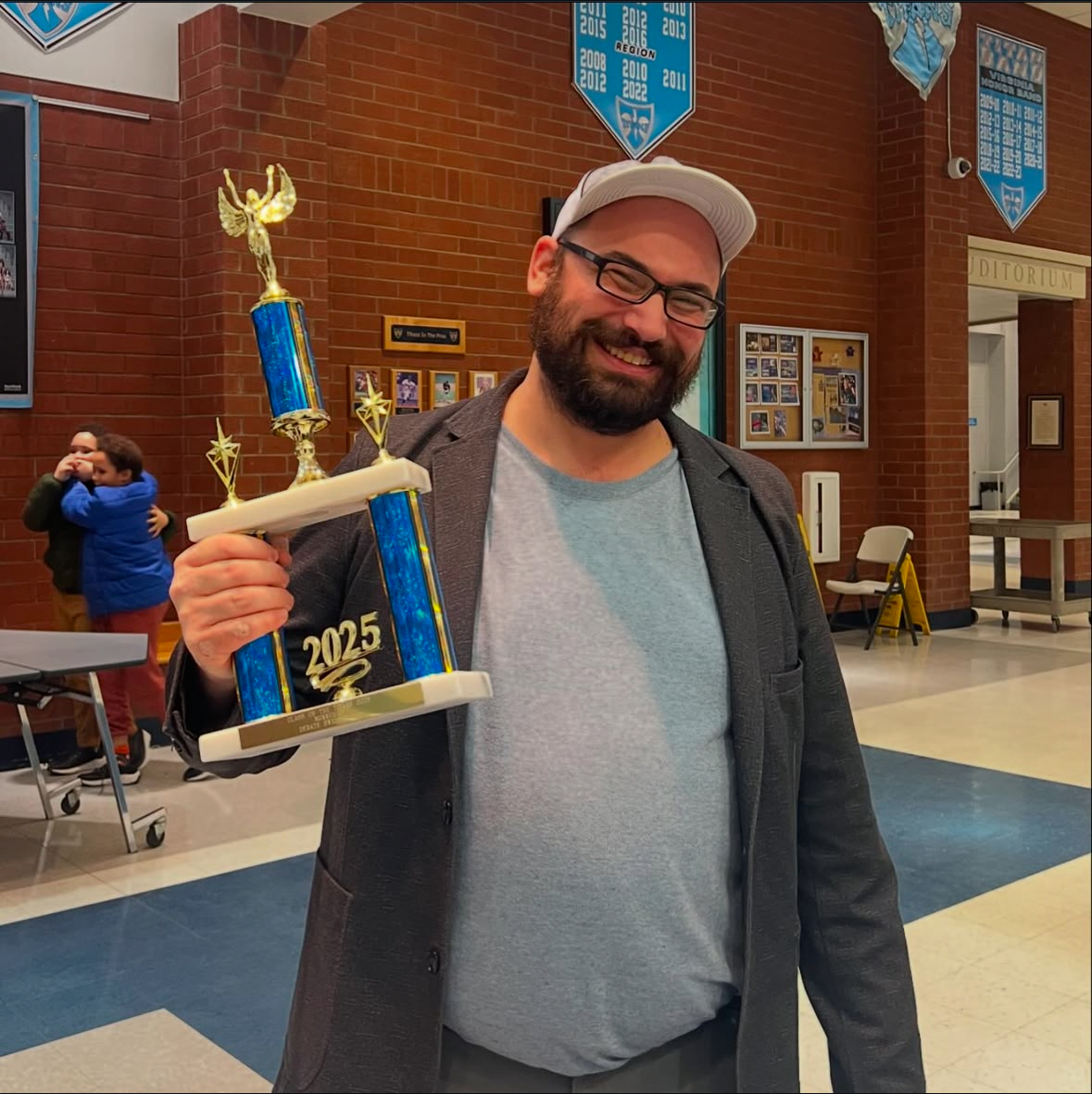 Debate club sponsor, Jaryd Engberg, poses with trophy after winning a thumb war. 