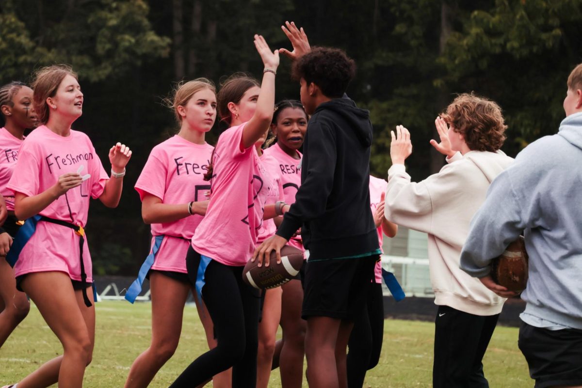 Freshman powder puff team high fives student coaches.